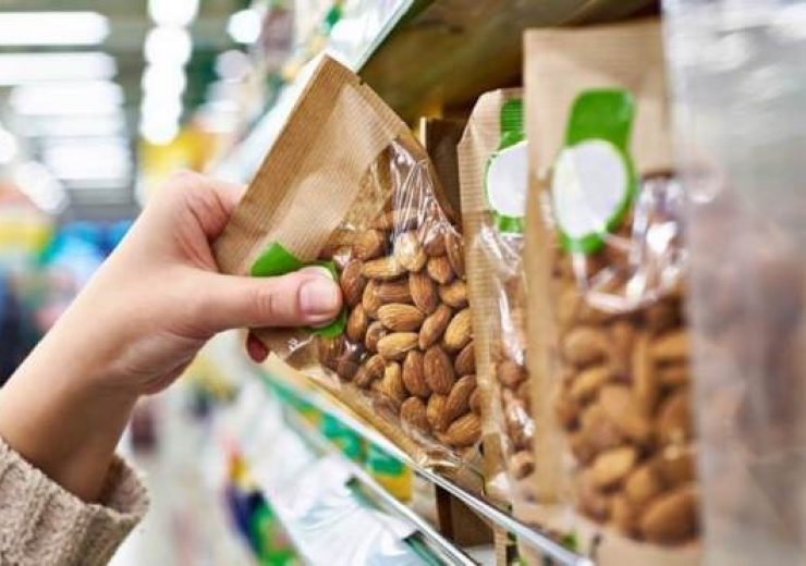 Hand of the buyer with the packaging of almond nuts in the store